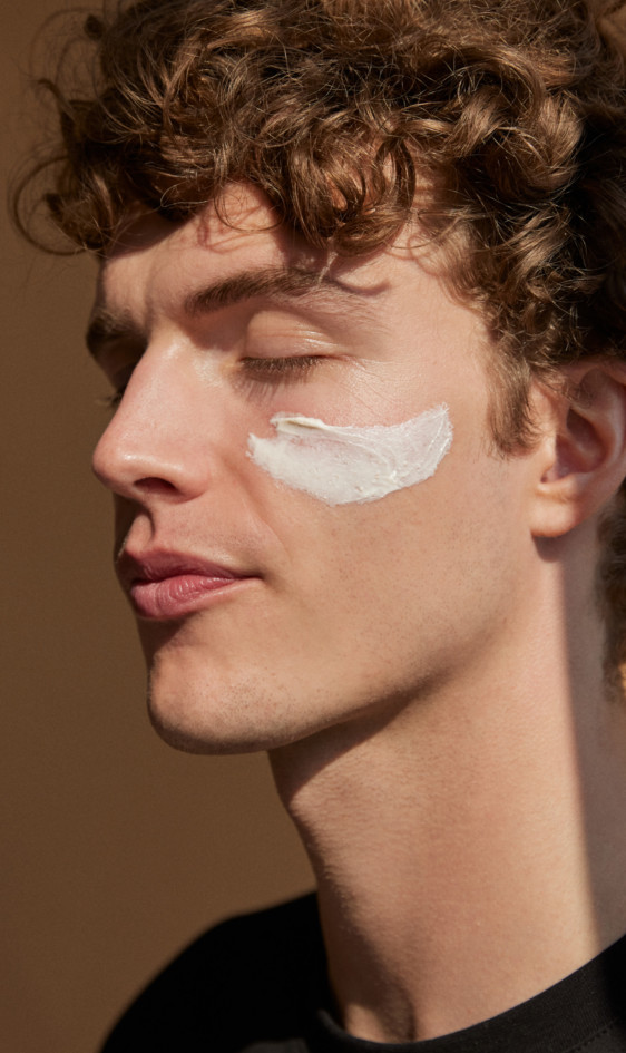 Un homme qui a les yeux fermés et qui a un gommage crème sur le visage